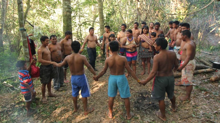 Des Indiens Ka’apor (hommes , femmes et enfants) forment un cercle en se tenant par la main dans la forêt tropicale