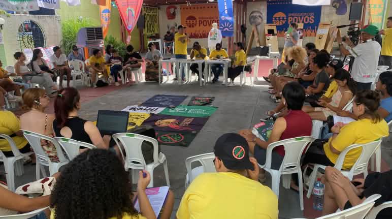 Une trentaine de personnes assises sur des chaises forment un cercle dans une salle de réunion