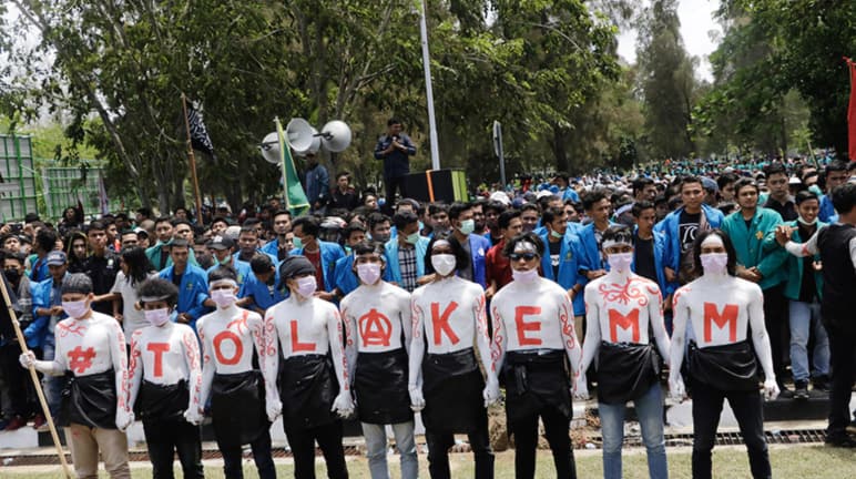 Neufs manifestants affichent "NON à EMM" en grosses lettres sur leur torse