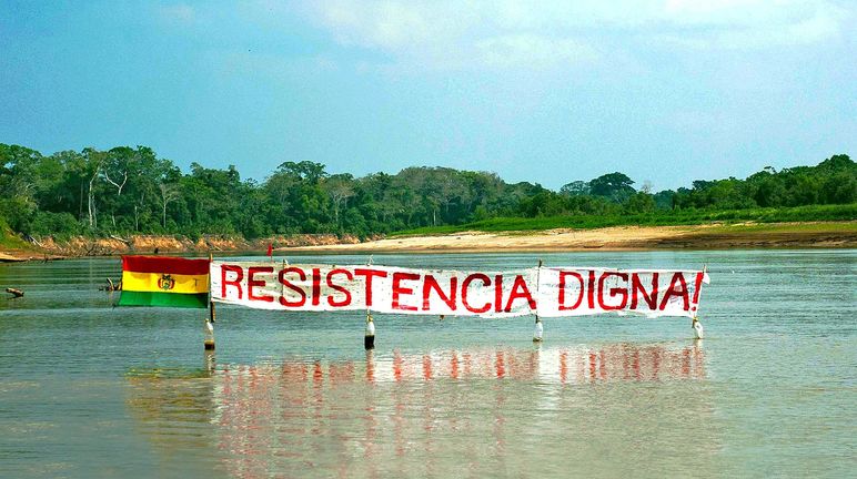 Bannière sur un fleuve dans la forêt tropicale de Bolivie : « Résister est une question de dignité » peut-on lire sur la bannière à côté du drapeau bolivien
