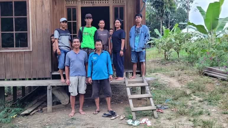 Les autochtones accueillent la visite de Sauvons la forêt Sept personnes devant une maison en bois