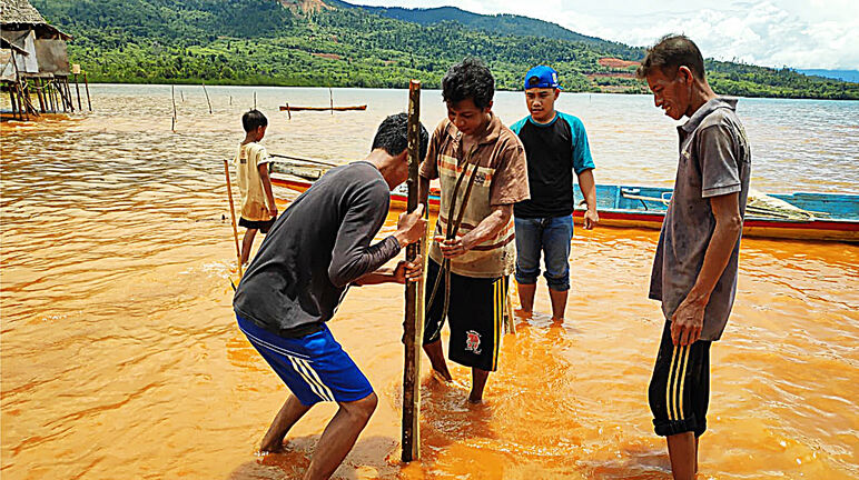 Des personnes les pieds dans la Boue jaune due à la pollution de la mer par le nickel en fusion