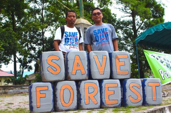 Nordin (à gauche) pose avec Udin derrière une pancarte posée à leurs pieds sur laquelle est écrit le slogan « Save forest »