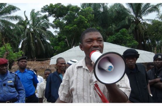 Surveillé par des militaires, l’ancien parlementaire de la Sierra Léone Hon. Musa Sama, parle dans un mégaphone dans une plantation de palmiers à huile