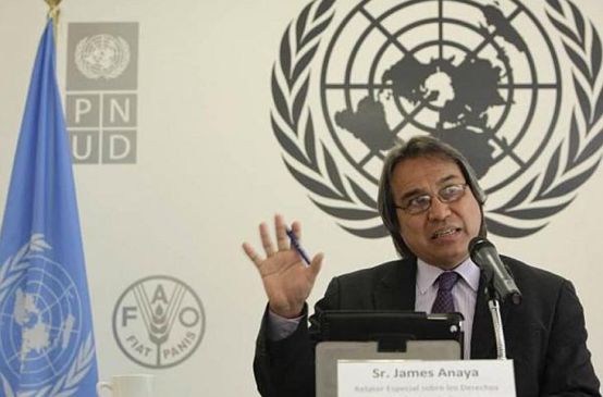 Photo de M. Anaya effectuant un discours avec comme le logo de l'ONU comme arrière plan