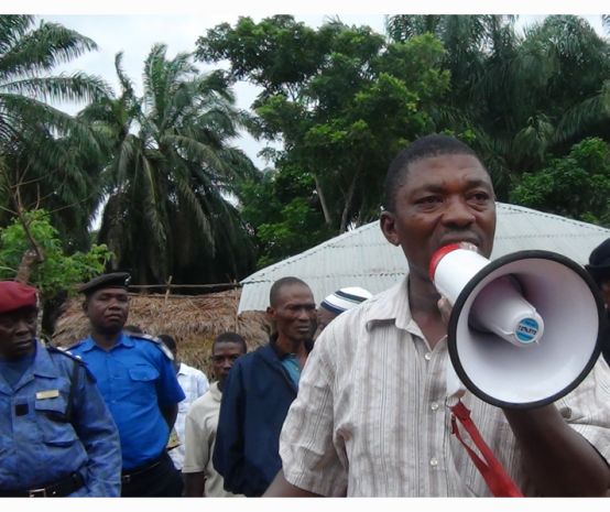 Surveillé par des militaires, l’ancien parlementaire de la Sierra Léone Hon. Musa Sama, parle dans un mégaphone dans une plantation de palmiers à huile
