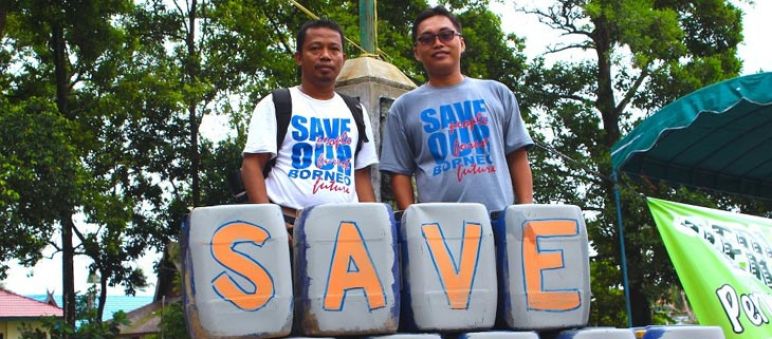 Nordin et Udin (à droite) de notre organisation partenaire Save our Borneo Nordin (à gauche) pose avec Udin derrière une pancarte posée à leurs pieds sur laquelle est écrit le slogan « Save forest »