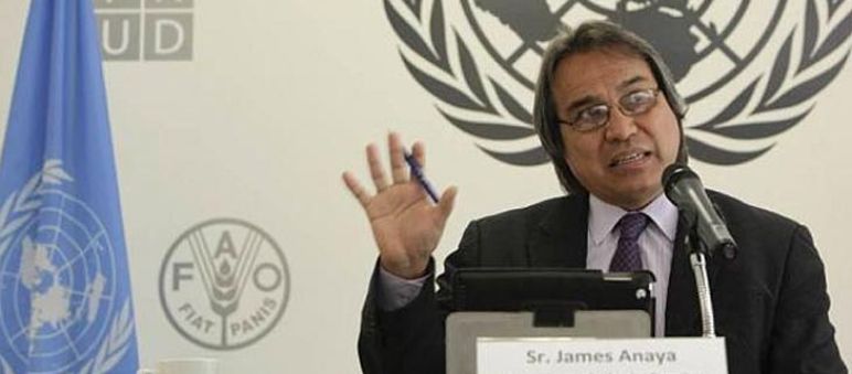 James Anaya, Rapporteur Spécial des Nations Unies sur le droit des Peuples Autochtones Photo de M. Anaya effectuant un discours avec comme le logo de l'ONU comme arrière plan
