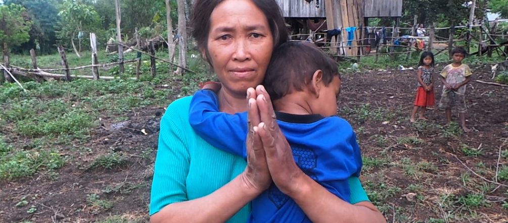Le sucre pour les Européens, la misère pour les Cambodgiens Une femme chassée de ses terres se tient devant un habitat de fortune (qu’on lui souhaite) provisoire. Avec son enfant accroché à son cou, elle tient ses mains jointes pour demander de l’aide.
