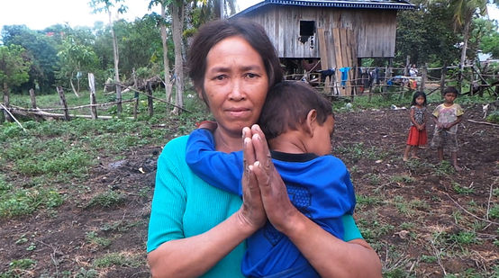 Une femme chassée de ses terres se tient devant un habitat de fortune (qu’on lui souhaite) provisoire. Avec son enfant accroché à son cou, elle tient ses mains jointes pour demander de l’aide.