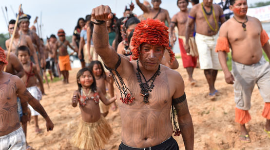 Les Mundurucús manifestent. Au premier plan, un Indien tatoué le point levé.