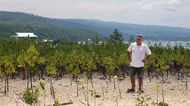 Un planteur de mangroves pose devant la côte reboisée