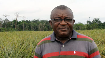 Le défenseur de la nature Odey Oyama devant une monoculture d’ananas