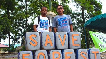 Nordin (à gauche) pose avec Udin derrière une pancarte posée à leurs pieds sur laquelle est écrit le slogan « Save forest »