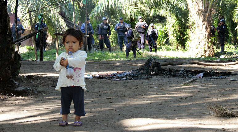 Petite fille effrayée (au premier plan) par les paramilitaires armés (à l'arrière plan)