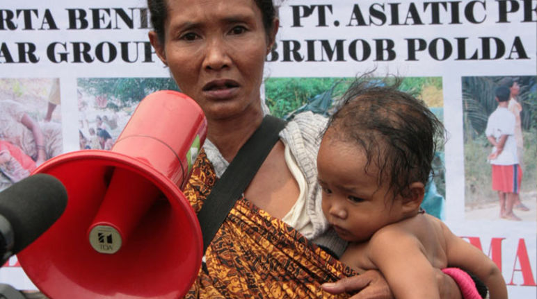 Ida et Agung sont en Europe avec 6 autres activistes indonésiens. Une femme portant son enfant avec un mégaphone