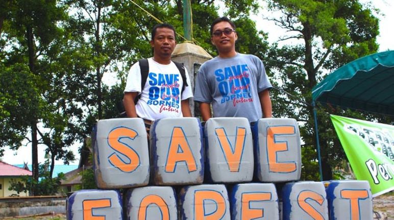 Nordin et Udin (à droite) de notre organisation partenaire Save our Borneo Nordin (à gauche) pose avec Udin derrière une pancarte posée à leurs pieds sur laquelle est écrit le slogan « Save forest »