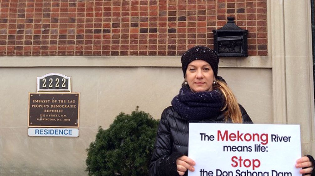 L’activiste Elisa Norio devant l’ambassade du Laos à Washington Devant la porte d’entrée de l’ambassade du Laos à Washington, lactiviste Elisa Norio tient une pancarte portant l’inscription « The Mekong River means life: stop the Don Sahong Dam »